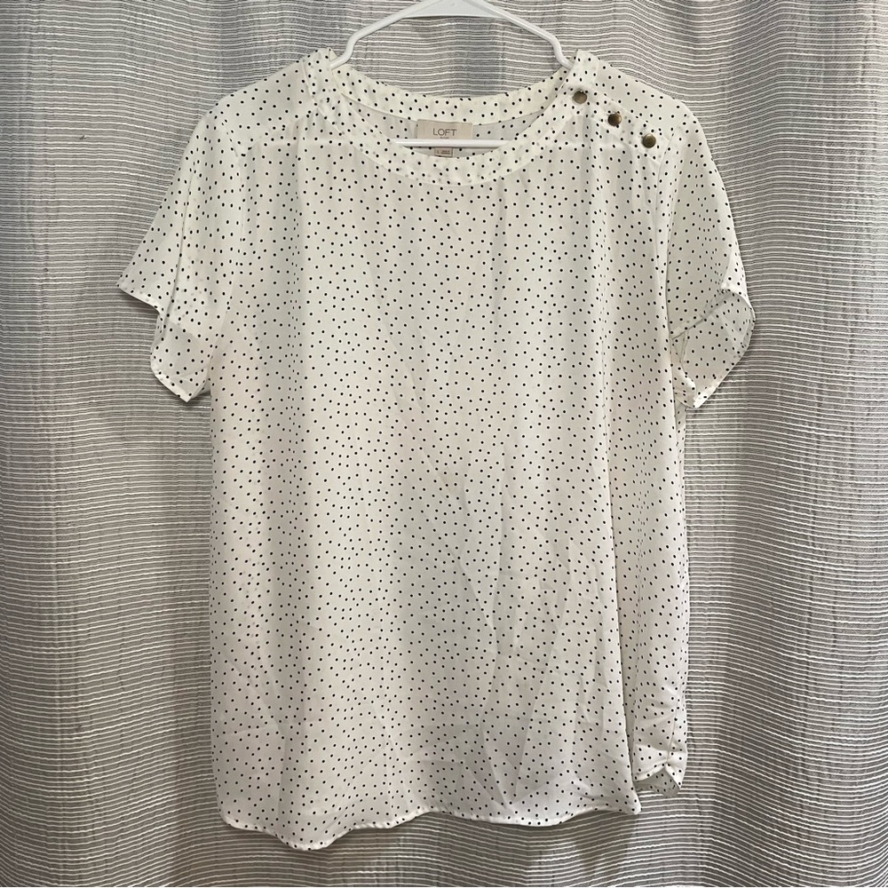 White blouse with black polka dots and faux brass buttons on the left shoulder